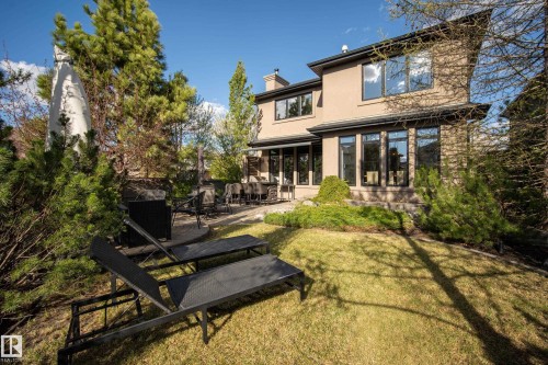 Expansive rear yard featuring a stone patio, lush lawn, mature trees, and shrubs - 2760 Watcher Way, Edmonton, AB - Outdoor