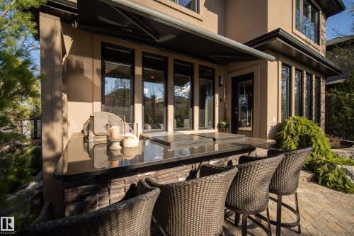Outdoor kitchen featuring a polished dark countertop, built-in grill, and stone-clad base - 2760 Watcher Way, Edmonton, AB - Outdoor With Deck Patio Veranda