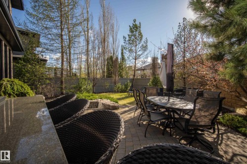 Expansive paver patio featuring a built-in bar with a stone countertop, a secondary dining area, mature landscaping, and a manicured lawn - 2760 Watcher Way, Edmonton, AB - Outdoor With Deck Patio Veranda
