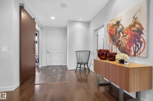 Entryway with rich wood-finish flooring, a contemporary sliding barn door, recessed lighting, and a white paneled door - 2760 Watcher Way, Edmonton, AB - Indoor Photo Showing Other Room