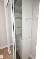 Integrated closet system featuring white shelving units and three drawers with metal pulls - 
