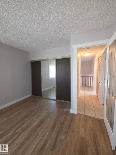 Room featuring wood-finish flooring, light grey painted walls, and a popcorn ceiling - 16 South Ram Crescent, Devon, AB - Indoor Photo Showing Other Room