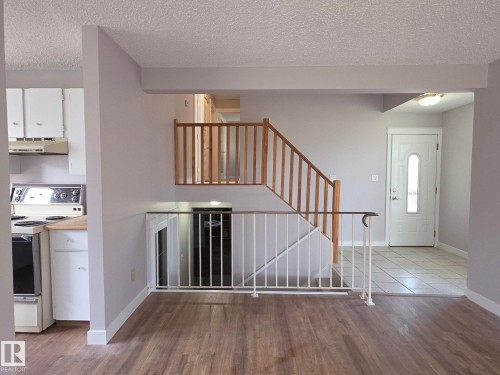 Inviting entry area featuring a white paneled door with decorative glass, ceramic tile flooring, and a stairway with wood railing - 16 South Ram Crescent, Devon, AB - Indoor