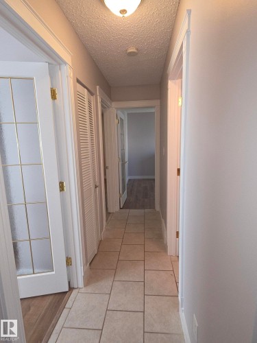 Hallway featuring tile flooring, neutral wall paint, white trim, and a ceiling-mounted light fixture - 16 South Ram Crescent, Devon, AB - Indoor Photo Showing Other Room