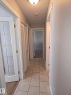 Hallway featuring tile flooring, neutral wall paint, white trim, and a ceiling-mounted light fixture - 