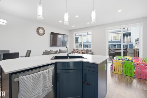 Kitchen island featuring a dual-basin sink, stainless steel dishwasher, and white countertop - 2284 Chokecherry Close, Edmonton, AB - Indoor Photo Showing Kitchen With Double Sink