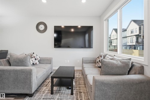Bright living area featuring white walls, recessed lighting, and large windows with white trim - 2284 Chokecherry Close, Edmonton, AB - Indoor Photo Showing Living Room