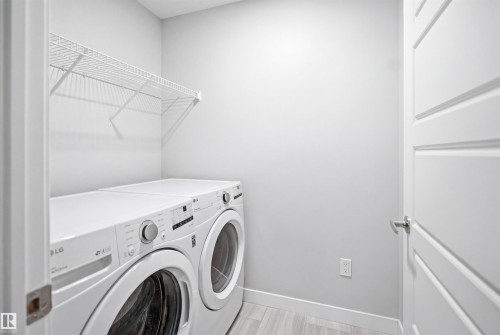 Dedicated laundry area featuring a wire storage shelf, light wood-finish flooring, and a paneled interior door with a brushed chrome handle - 2284 Chokecherry Close, Edmonton, AB - Indoor Photo Showing Laundry Room