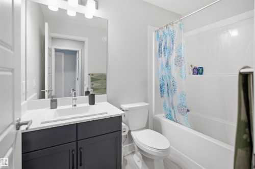Bathroom featuring a vanity with a white countertop and rectangular undermount sink, a large wall-mounted mirror, a three-light fixture, and a white toilet - 2284 Chokecherry Close, Edmonton, AB - Indoor Photo Showing Bathroom