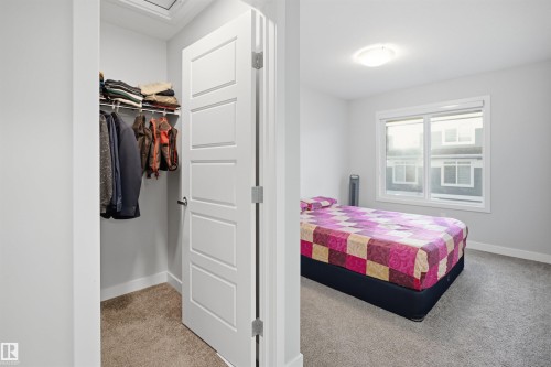 Carpeted room featuring light gray walls, a window with white trim, and a built-in closet with shelving and a hanging rod - 2284 Chokecherry Close, Edmonton, AB - Indoor Photo Showing Bedroom