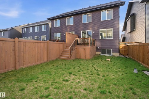 Enclosed backyard featuring a wood deck with glass panel railings, direct access from the house via sliding glass doors, exterior siding, and a privacy fence - 2284 Chokecherry Close, Edmonton, AB - Outdoor With Exterior