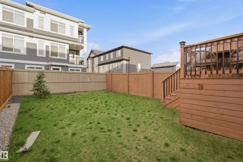 Expansive fenced yard featuring a wooden deck with railing and stairs, a mature evergreen, and a gravel border - 2284 Chokecherry Close, Edmonton, AB - Outdoor
