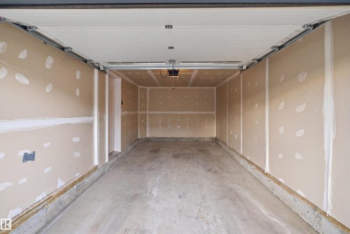 Spacious garage featuring a concrete floor, unpainted drywall walls, and a white paneled garage door with track system - 2284 Chokecherry Close, Edmonton, AB - Indoor Photo Showing Garage