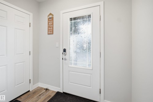 Entry door with decorative glass inserts, modern smart lock hardware, and bright white trim - 2284 Chokecherry Close, Edmonton, AB - Indoor Photo Showing Other Room