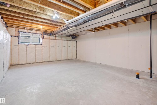 Unfinished lower level featuring exposed ceiling joists, concrete flooring, perimeter wall insulation, a visible egress window, and utility lines - 2284 Chokecherry Close, Edmonton, AB - Indoor Photo Showing Basement
