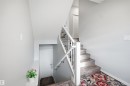 Staircase featuring wood-finish treads, white risers, and a white handrail with black iron balusters - 2284 Chokecherry Close, Edmonton, AB  - Indoor Photo Showing Other Room 