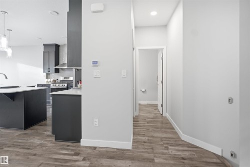 Open-concept kitchen featuring dark cabinetry, white countertops, stainless steel appliances, and pendant lighting - 2284 Chokecherry Close, Edmonton, AB - Indoor