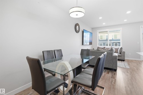 Open-concept living space with wood-finish flooring, recessed lighting, and a large sliding window - 2284 Chokecherry Close, Edmonton, AB - Indoor Photo Showing Dining Room