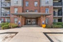 Brick and siding exterior featuring a covered entryway with columns, glass entry doors, multiple windows, and upper-level balconies with black railings - 217 667 Watt Boulevard, Edmonton, AB  - Outdoor With Balcony With Exterior 