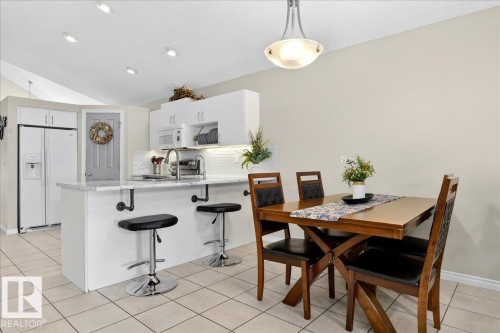 Kitchen and dining area featuring white cabinetry, a kitchen island with a white countertop, recessed lighting, and tile flooring - 3518 18 Street, Edmonton, AB - Indoor Photo Showing Dining Room
