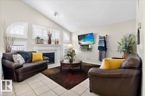 Living room featuring a vaulted ceiling, a fireplace with a white mantel, and tiled flooring - 3518 18 Street, Edmonton, AB - Indoor Photo Showing Living Room With Fireplace