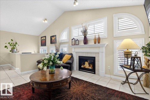 Living space featuring a vaulted ceiling, a fireplace with a white mantel, and windows with white shutters - 3518 18 Street, Edmonton, AB - Indoor Photo Showing Living Room With Fireplace