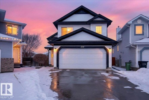 The property features a two-story exterior with white siding and dark trim, illuminated by exterior lighting - 3518 18 Street, Edmonton, AB - Outdoor