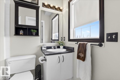 This bathroom features a white vanity with a dark countertop and a white sink, illuminated by a four-bulb light fixture - 3518 18 Street, Edmonton, AB - Indoor Photo Showing Bathroom