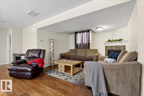 The living area features hardwood floors and a corner fireplace with a tiled surround and white mantel - 3518 18 Street, Edmonton, AB - Indoor Photo Showing Living Room With Fireplace