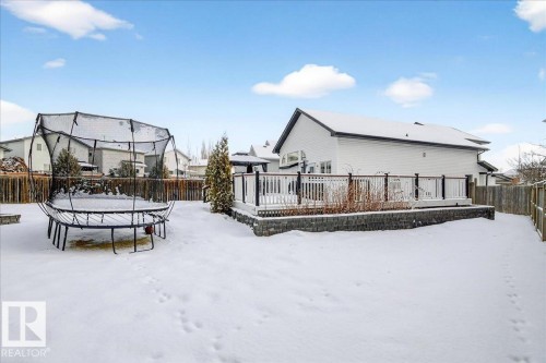 The property includes a spacious backyard with a snow-covered lawn, a wooden privacy fence, and a raised deck with a dark railing - 3518 18 Street, Edmonton, AB - Outdoor