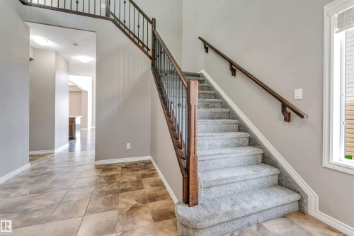 Entry foyer featuring a carpeted staircase with dark wood handrails and wrought iron balusters - 2138 32B Street, Edmonton, AB - Indoor Photo Showing Other Room