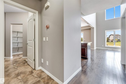 Expansive foyer featuring wood-finish flooring, high ceilings, multiple windows, and a coat closet with adjustable shelving - 2138 32B Street, Edmonton, AB - Indoor Photo Showing Other Room