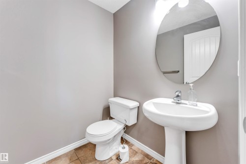 Pedestal sink with chrome faucet, complemented by a large oval mirror - 2138 32B Street, Edmonton, AB - Indoor Photo Showing Bathroom