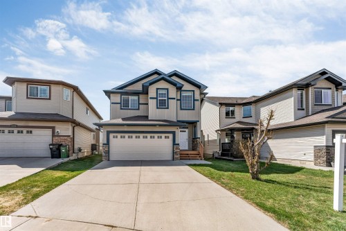 Two-story residence featuring light-toned siding with contrasting dark trim accents and a prominent two-car garage - 2138 32B Street, Edmonton, AB - Outdoor With Facade