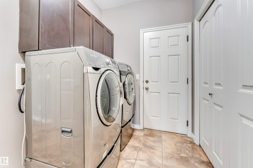 Dedicated laundry area featuring dark wood-finish cabinetry, light gray walls, and tile flooring - 2138 32B Street, Edmonton, AB - Indoor Photo Showing Laundry Room