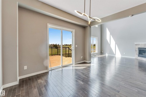 Spacious interior featuring wood-finish flooring, a contemporary ceiling fixture, and a fireplace with a stone surround - 2138 32B Street, Edmonton, AB - Indoor Photo Showing Living Room With Fireplace