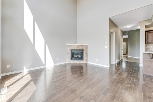 Living area featuring a floor-to-ceiling fireplace with a tile surround, dark wood-finish flooring, and high ceilings - 2138 32B Street, Edmonton, AB - Indoor Photo Showing Living Room With Fireplace
