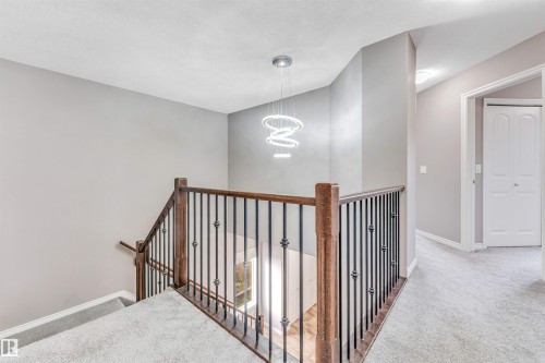 Upper-level landing featuring a contemporary chandelier, light gray wall paint, and plush carpet flooring - 2138 32B Street, Edmonton, AB - Indoor Photo Showing Other Room