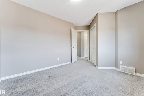 Neutral-toned interior room featuring light gray carpet, white baseboards, and a white ceiling with a flush-mount light fixture - 2138 32B Street, Edmonton, AB - Indoor Photo Showing Other Room