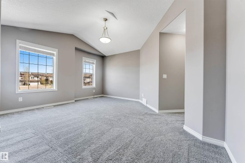 Spacious room featuring vaulted ceilings, plush grey carpeting, and two multi-pane windows - 2138 32B Street, Edmonton, AB - Indoor Photo Showing Other Room