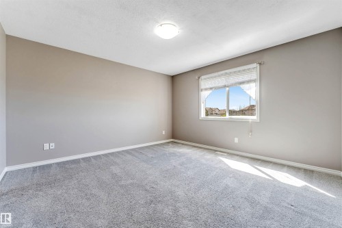 Spacious room featuring neutral wall tones, gray carpet flooring, a window with horizontal blinds, and a flush-mount ceiling light fixture - 2138 32B Street, Edmonton, AB - Indoor Photo Showing Other Room
