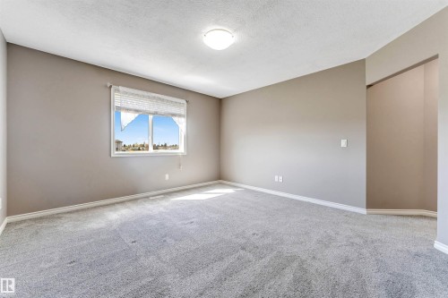 Spacious room featuring neutral-toned walls, light grey carpeting, white baseboards, and a bright window - 2138 32B Street, Edmonton, AB - Indoor Photo Showing Other Room