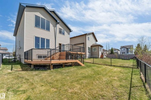 Expansive backyard featuring a fenced perimeter, a raised wood deck with black metal railings, and a two-story exterior with horizontal siding and multiple large windows - 2138 32B Street, Edmonton, AB - Outdoor With Deck Patio Veranda
