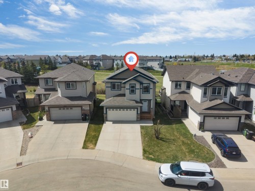 Contemporary two-story residence featuring a front-facing attached garage, concrete driveway, and a front lawn with a decorative tree - 2138 32B Street, Edmonton, AB - Outdoor With Facade