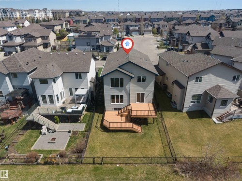 Expansive backyard featuring a multi-level wood-finish deck with glass panel railings, a ground-level paver patio, and a fire pit - 2138 32B Street, Edmonton, AB - Outdoor