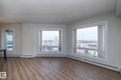 Spacious room featuring wood-finish flooring, light grey walls, and two large windows with horizontal blinds - 