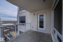 Private balcony featuring a concrete floor, glass railing, and high-rise cityscape - 