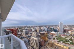 Expansive city panorama from a high-rise balcony featuring a glass and white railing - 