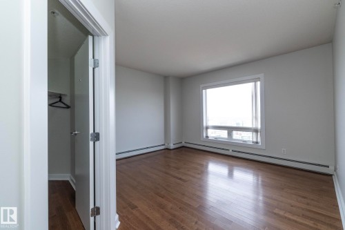 Bright room with wood-finish flooring, a large window, white walls, and baseboard heating - 3104 10152 104 Street, Edmonton, AB - Indoor Photo Showing Other Room