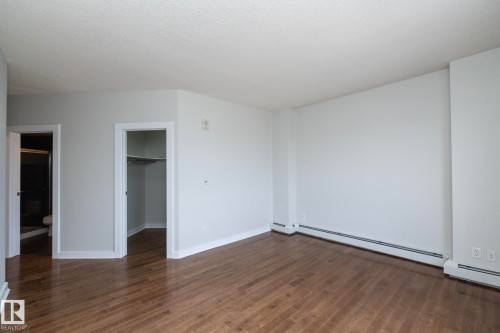 Expansive room featuring rich wood-finish flooring, crisp white walls, and bright white trim - 3104 10152 104 Street, Edmonton, AB - Indoor Photo Showing Other Room